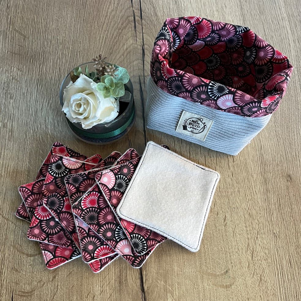 Panier en velours côtelé gris et ses lingettes lavables à motifs éventails rose et rouge disposées devant
