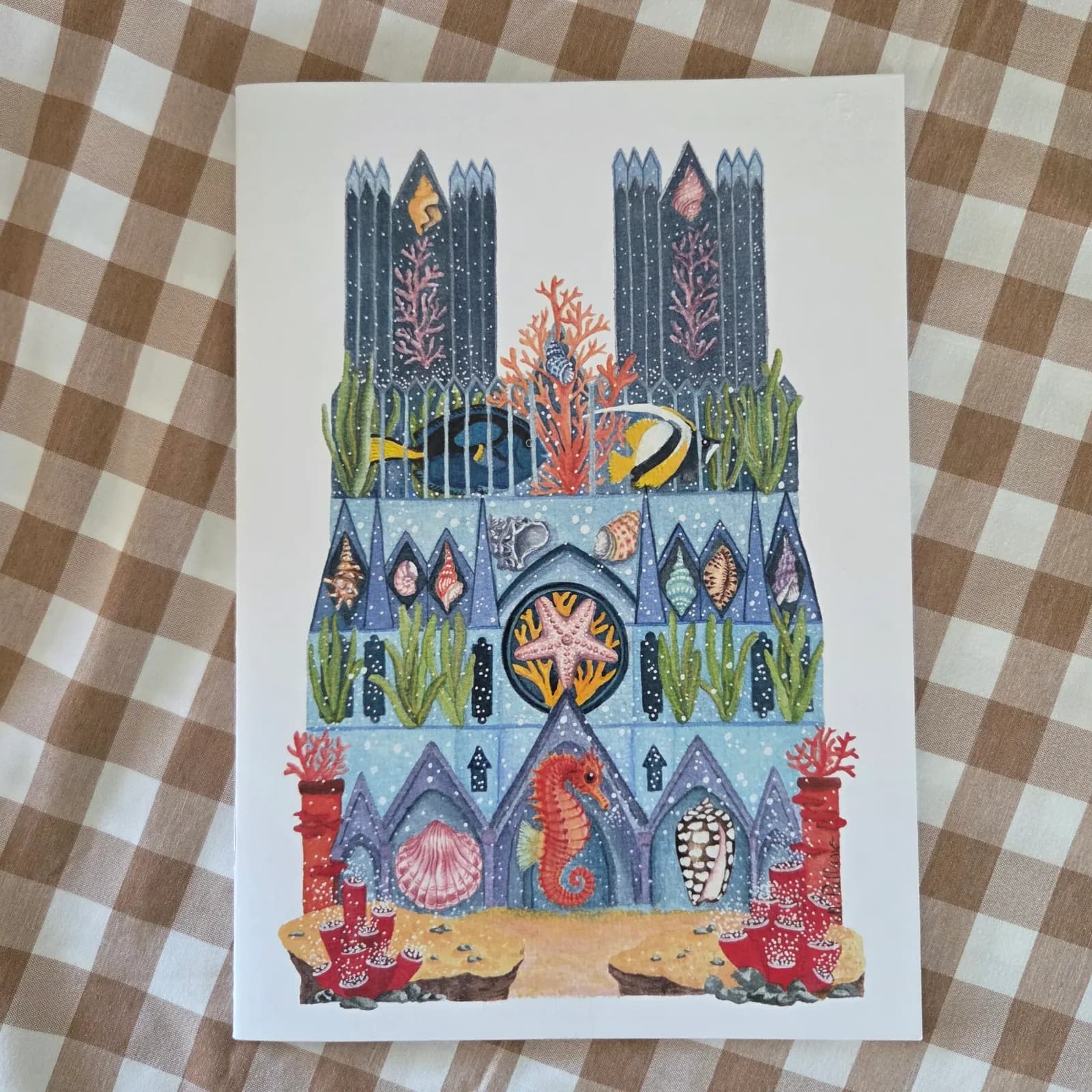 Couverture illustrée du carnet avec une cathédrale sous-marine, un hippocampe, des coraux et coquillages.